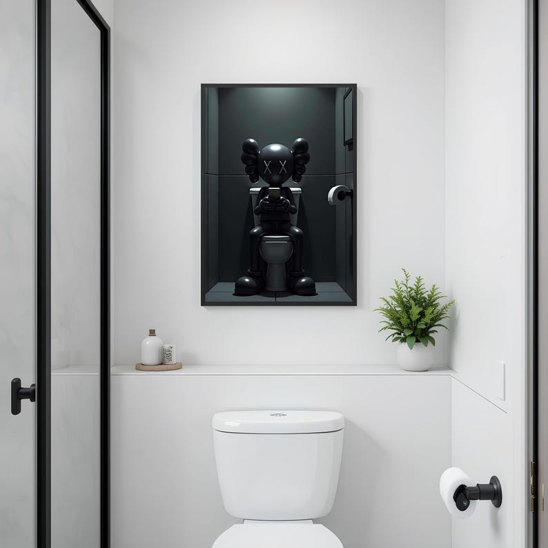 May include: A modern bathroom scene featuring a white toilet and a framed black sculpture of a figure seated on a toilet. A small potted plant and a shelf with accessories add to the minimalist decor. The walls are white, and the door frame is black.