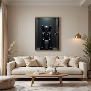 May include: A framed artwork depicts a black cartoon figure seated on a toilet in a dark bathroom setting. The figure has large, round ears and crossed-out eyes. The artwork is displayed above a beige sofa with several pillows.