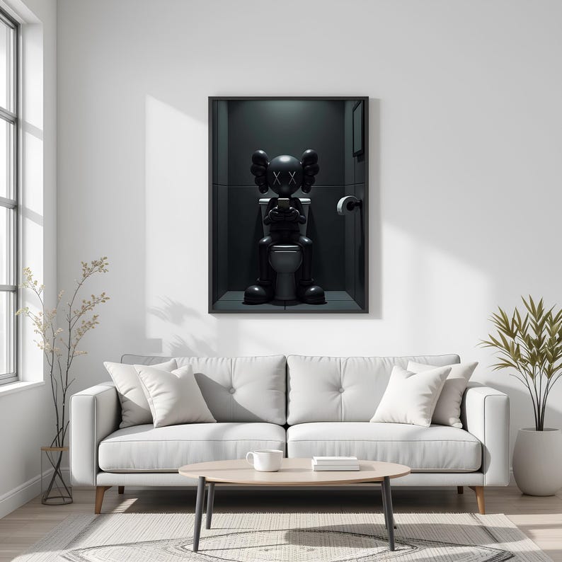 May include: Framed artwork featuring a black figure with crossed-out eyes, seated on a toilet while holding a phone. The figure is in a dark, minimalist bathroom setting. The artwork is displayed above a white sofa.