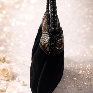 May include: Black velvet handbag with a beaded top and a black beaded handle. The top of the bag features a pattern of gold, brown, and silver beads. The handle is made of large, rounded black beads.