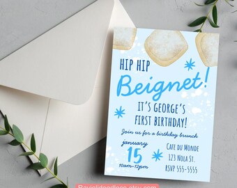 May include: A light blue birthday invitation with the text "HIP HIP Beignet!" and "IT'S GEORGE'S FIRST BIRTHDAY!". The invitation includes details for a brunch on January 15th at Cafe Du Monde, 123 NOLA ST. and the RSVP number.