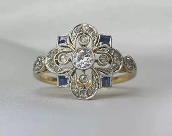 May include: An antique gold ring with a central round diamond and surrounding smaller diamonds. The ring features four square blue gemstones and an ornate, filigree design. The ring is set on a gold band.