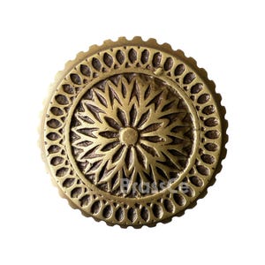 Può includere: Un pomello rotondo in ottone anticato con un motivo floreale al centro e un bordo decorativo. Il pomello ha il testo "Brass Co". Questo hardware decorativo è adatto per mobili o armadi.