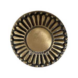 Può includere: Pomello per armadio rotondo in ottone antico con design a raggiera. Il pomello presenta un'area circolare centrale circondata da dettagli a forma di petalo e un bordo esterno perlato. La superficie ha una calda patina invecchiata.