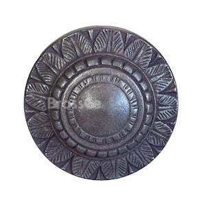 Può includere: Pomello per armadio circolare in stile antico con finitura metallica scura. Il pomello presenta un cerchio centrale rialzato circondato da anelli concentrici e un motivo dettagliato a forma di foglia sul bordo esterno. La parola "BrassSea" è visibile.