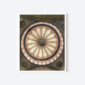 May include: A framed print of a mosque ceiling. The ceiling is a circular design with a central medallion and radiating spokes. The design incorporates red, blue, and gold accents, with intricate patterns and calligraphy.