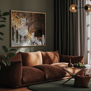 Puede incluir: Un sof&aacute; de terciopelo marr&oacute;n con una mesa de caf&eacute; de vidrio en una sala de estar con una gran impresi&oacute;n enmarcada de un gran sal&oacute;n con candelabros. La habitaci&oacute;n tiene paredes verdes y cortinas blancas.