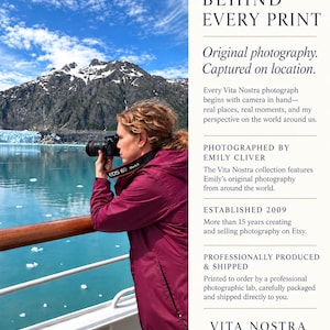May include: A person in a maroon jacket uses a black DSLR camera to photograph a glacier and blue water from a ship deck. Text on the right reads: BEHIND EVERY PRINT, Original photography. Captured on location, PHOTOGRAPHED BY EMILY CLIVER, ESTABLISHED 2009, PROFESSIONALLY PRODUCED & SHIPPED, VITA NOSTRA EXPLORE. DREAM. DISCOVER.