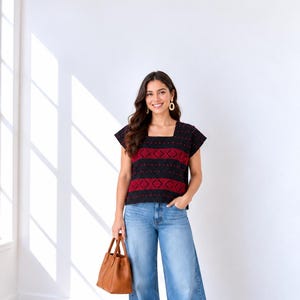 May include: A black short-sleeved top featuring a square neckline and horizontal bands of red geometric diamond patterns and small red dots, paired with light blue wide-leg denim jeans, white sneakers, and a tan leather handbag.