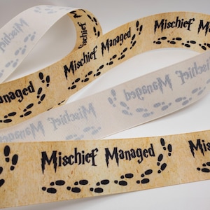 May include: Ribbon with the text "Mischief Managed" and black footprints. The ribbon has a parchment-like background and is in a curled arrangement. A second ribbon with the same text and footprints is also visible, along with a third ribbon with the text "idei M".
