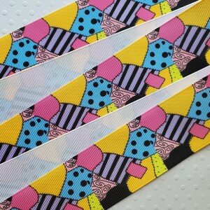 May include: Multicolored ribbon with a repeating pattern of patchwork-style designs featuring black, white, pink, blue, and yellow. The design includes polka dots, stripes, and swirls.