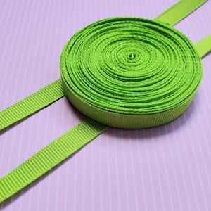 May include: A roll of bright green grosgrain ribbon with a textured surface. The ribbon is approximately 1 inch wide.