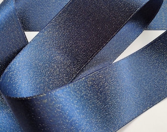 May include: A roll of navy blue satin ribbon with gold glitter. The ribbon is folded and has a slight sheen.