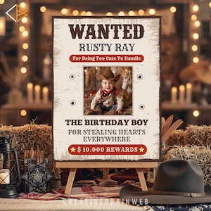 May include: A rustic-themed birthday sign on an easel, featuring the text "WANTED RUSTY RAY" and a photo of a baby in a cowboy hat. The sign reads "The Birthday Boy For Stealing Hearts Everywhere" with a reward of $10,000.