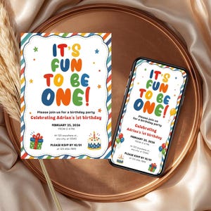 Op de afbeelding: Een verjaardagsuitnodiging en een smartphone met hetzelfde ontwerp. De uitnodiging en het telefoonscherm tonen de tekst "IT'S FUN TO BE ONE!" in heldere kleuren. Details zijn onder meer de datum, tijd en RSVP-informatie.