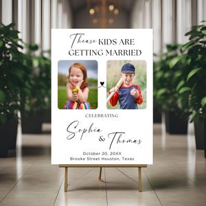 Könnte beinhalten: Ein weißes Hochzeitsschild auf einer goldenen Staffelei. Das Schild zeigt zwei Fotos von Kindern mit dem Text "Thease KIDS ARE GETTING MARRIED" darüber. Darunter steht "Celebrating Sophia & Thomas" sowie Datum und Ort.