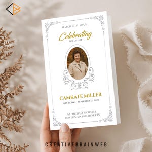 May include: A white memorial card with gold and gray accents. The card features the text "Celebrating the Life of" and the name "CAMKATE MILLER" with birth and death dates. A photo is centered within an oval frame. The card is held by a hand.