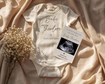 May include: A cream-colored baby onesie with the text "Baby Theodore" and a heart symbol. A card with an ultrasound image and the text "A Little Miracle On The Way Baby Theodore" is next to the onesie. The expected date is February 20YY.