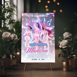 May include: A party sign on a gold easel with the text "Lets Celebrate!" and "Welcome to Madison's 10th Birthday October 15. 2026". The sign features a graphic of three animated figures in white outfits.