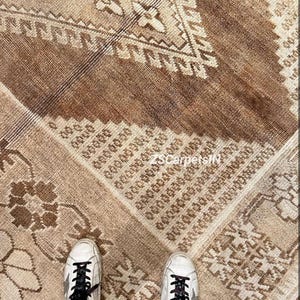 Könnte beinhalten: Nahaufnahme eines Vintage-Teppichs mit einem verblichenen, abgenutzten Aussehen. Der Teppich zeigt ein komplexes geometrisches Muster in Braun-, Beige- und Cremetönen. Das Design umfasst florale und geometrische Motive. Der Text "ZSCarpetsIN" ist sichtbar.