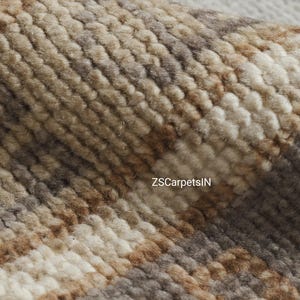 May include: Close-up of a textured rug with a woven pattern. The rug features a blend of neutral colors, including beige, brown, and gray, creating a warm and inviting aesthetic. The text "ZSCarpetsIN" is visible on the rug.