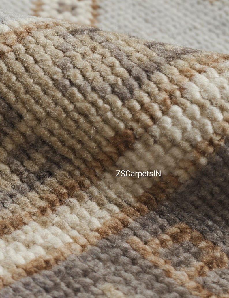 May include: Close-up of a textured rug with a woven pattern. The rug features a blend of neutral colors, including beige, brown, and gray, creating a warm and inviting aesthetic. The text "ZSCarpetsIN" is visible on the rug.
