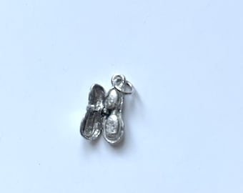 May include: Silver charm in the shape of a peanut with the shell open and two peanuts inside.