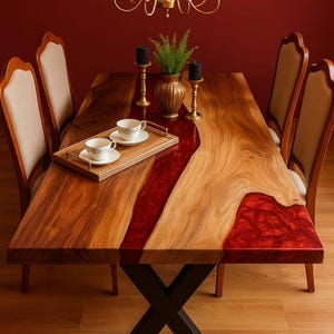 Peut inclure: Une table à manger en bois faite à la main avec un motif de rivière en résine rouge. La table est entourée de quatre chaises rembourrées. Un plateau avec des tasses à thé et un lustre à bougies sont sur la table. La table mesure environ 200 cm de long.
