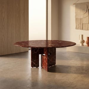 Könnte beinhalten: Ein runder Tisch aus rotem Marmor mit einem einzigartigen geometrischen Fuß. Die Tischplatte hat ein marmoriertes Muster mit weißen Adern. Der Tisch hat einen Durchmesser von ca. 122 cm und ist ein Blickfang für jeden Wohnraum.