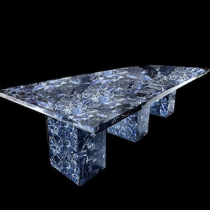 May include: A rectangular table with a striking blue and white patterned surface. The table has three solid, rectangular supports. The table's design is modern and eye-catching, perfect for a dining or living room setting.