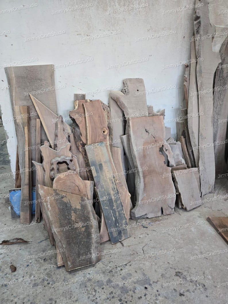 May include: A collection of raw, unfinished wood slabs and planks, varying in size and shape, leaning against a white wall. The wood tones range from light tan to dark brown, showcasing natural grain patterns. The image includes the text "JimmysCraftStudio".