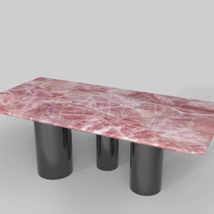Könnte beinhalten: Rechteckiger Tisch mit einer rosa-weiß gemusterten Tischplatte, getragen von drei dunkelgrauen zylindrischen Beinen. Die Tischoberfläche hat ein marmoriertes Aussehen. Das Design ist modern und minimalistisch. Maße in Zentimetern.