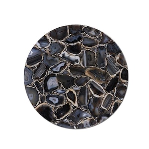 May include: A circular tabletop made from polished agate stone. The stone has a mosaic pattern of black, grey, and white pieces with a polished finish. The agate pieces are arranged in a circular design.
