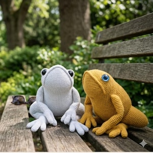 Puede incluir: Dos peluches de rana de ganchillo sentados en un banco de madera. Uno es gris claro con ojos negros, el otro es amarillo mostaza con ojos azules. Las ranas tienen detalles, incluyendo patas palmeadas y una superficie texturizada.