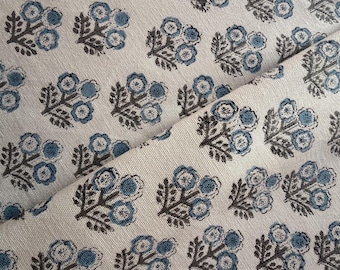 May include: Cream-colored fabric with a repeating pattern of stylized blue and brown floral bouquets. The fabric is folded, showing the texture and design. Ideal for home decor or crafting projects.