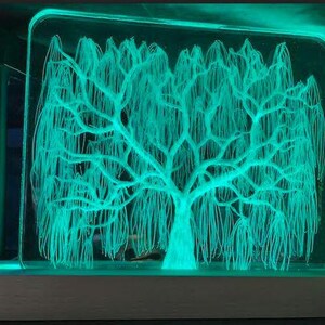 May include: A green illuminated glass sculpture of a weeping willow tree. The tree is detailed with intricate branches and leaves.
