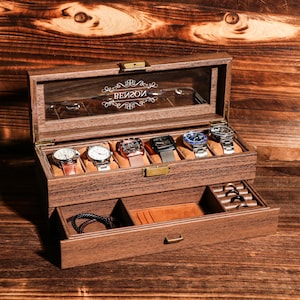 Puede incluir: Una caja de reloj de madera con tapa de cristal, que muestra seis relojes con varios colores de correa. La caja tiene un cajón con compartimentos para joyas y accesorios. La palabra "BEIZON" está grabada en el cristal.