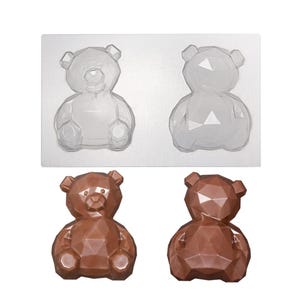 Peut inclure: Un moule rectangulaire en plastique transparent présentant deux cavités en forme d'oursons géométriques, accompagné de deux oursons en chocolat marron finis avec des surfaces facettées correspondant à la forme du moule.