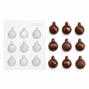 May include: A clear plastic mould tray featuring nine distinct spherical ornament cavities with various embossed patterns, accompanied by nine corresponding dark brown chocolate ornaments moulded into the same festive bauble shapes.