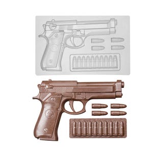 Peut inclure: Un pistolet et des balles en chocolat marron, à côté d'un moule en plastique transparent du même design. Le pistolet présente des détails complexes, notamment la gâchette et la poignée. Les balles sont également marron et détaillées.