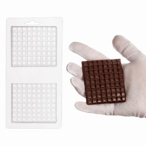 May include: A clear plastic rectangular mold featuring two square sections with a grid pattern of small indentations, alongside a dark brown square chocolate piece with a matching grid pattern of small raised squares on its surface.