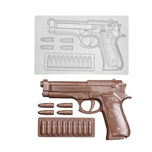 Op de afbeelding: Een doorzichtige plastic mal en een bijpassende bruine chocolade gietvorm van een semi-automatisch pistool, vier losse kogels en een rechthoekige strip met tien kogels, gerangschikt op een effen witte achtergrond.