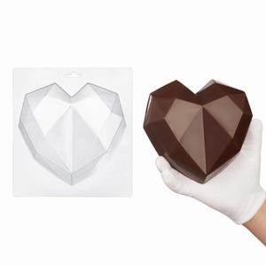 May include: A clear plastic heart-shaped mold with a geometric faceted design, alongside a solid dark brown chocolate heart featuring the same multi-faceted, angular structure, held by a hand wearing a white fabric glove.