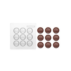 May include: A square white plastic mould with nine circular cavities featuring a relief design of a cake, accompanied by nine dark brown circular chocolate pieces, each embossed with the same cake design and the text Merry Christmas.
