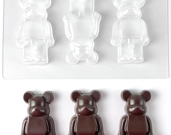 May include: A clear plastic rectangular mold featuring three bear-shaped cavities, with two bears oriented upright and one inverted. Below the mold are three dark brown bear-shaped figures cast from the mold, each with a smooth, glossy finish.