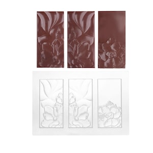 Pode incluir: Três barras de chocolate retangulares com um design floral, ao lado de um molde de plástico branco com o mesmo padrão de flores. As barras de chocolate são de cor castanho escuro e o molde é branco. O design floral é um relevo detalhado.