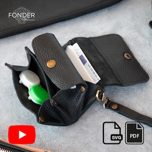 May include: Black leather wallet with multiple compartments, including one for contact lenses and another for cash. The wallet has a wrist strap and a snap closure. The word "FONDER" is visible in the upper left corner.