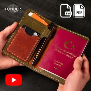 May include: Olive green leather passport holder with a rust-coloured cardholder and a black pen. The holder contains a burgundy passport and several cards. The text "FONDER Atelier" is visible in the upper left corner.