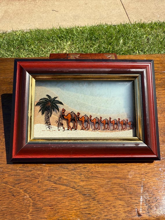 Hand-filled UAE camel scene sand picture using natural-color sand — a genuine artisan piece with a specific cultural narrative, not a factory repackage.