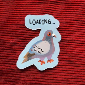 Peut inclure: Autocollant représentant un pigeon de dessin animé avec un corps bleu clair, des ailes marron et des pieds orange. Une bulle de dialogue au-dessus du pigeon dit "LOADING...". L'autocollant est sur un fond rouge texturé.